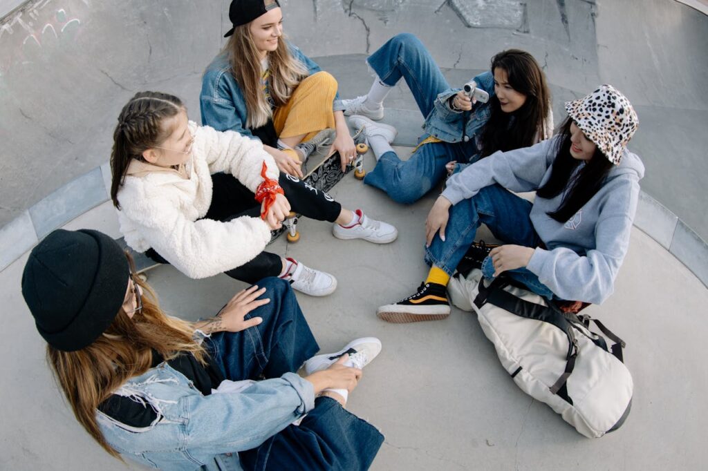 Five young women enjoy time together at a skate park, sharing laughter and friendship.